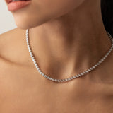 Model wearing the Bubble Tennis Necklace which is a classic Tennis Necklace featuring a row of round diamonds set in a silver chain. 
