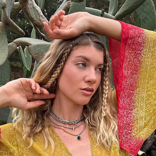 Blond girl with a landscape full of cactus, a red and yellow shirt and an Artizan Joyeria necklace