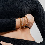 Model wearing the Chain Gang Bracelet Stack featuring three bracelets, a mix of gold and silver chains with triangle and star charms, accented with evil eye charm with sparkling rhinestones.