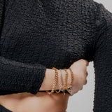 Model wearing the Chain Gang Bracelet Stack featuring three bracelets, a mix of gold and silver chains with triangle and star charms, accented with evil eye charm with sparkling rhinestones.