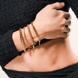 Model wearing the Chain Gang Bracelet Stack featuring three bracelets, a mix of gold and silver chains with triangle and star charms, accented with evil eye charm with sparkling rhinestones.