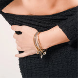 Model wearing the Chain Reaction Bracelet Stack featuring gold and silver chains with diamond-encrusted charms, including a snowflake, teardrop, and triangle.