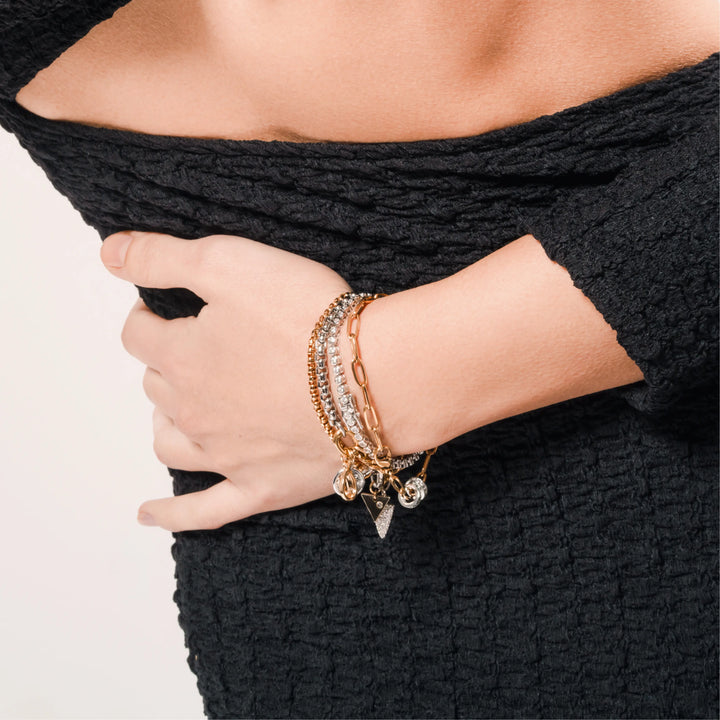 Model wearing the Chain Reaction Bracelet Stack featuring gold and silver chains with diamond-encrusted charms, including a snowflake, teardrop, and triangle.