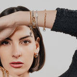 Model wearing the Chain Reaction Bracelet Stack featuring gold and silver chains with diamond-encrusted charms, including a snowflake, teardrop, and triangle.