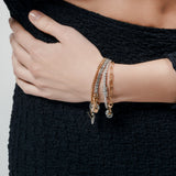 Model wearing the Chain Reaction Bracelet Stack featuring gold and silver chains with diamond-encrusted charms, including a snowflake, teardrop, and triangle.
