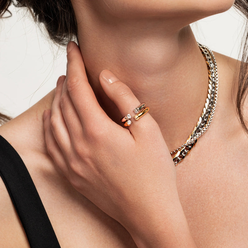 Model wearing the Crowned Thumb Ring in a mixed metal finish with sparkling pavé accents, styled with a bold chain necklace. 