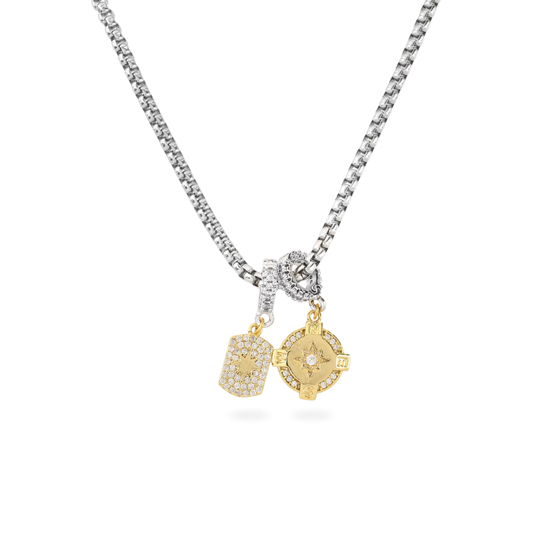 The Herradura Signature Charmed Tennis Set, which is a single-piece silver necklace, features a dazzling chain with two gold charms—one rectangular with shimmering accents and one circular with intricate star-inspired detailing—creating a striking mix of modern elegance and charm.