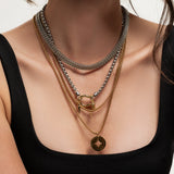 Model wearing the Herradura Layered Necklace Set featuring five mixed metal gold and silver chains with charms and a signature carabiner clasp.