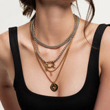 Model wearing the Herradura Layered Necklace Set featuring five mixed metal gold and silver chains with charms and a signature carabiner clasp. ||| GOLD