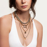The Herradura Layered Necklace Set, a set of four mixed-metal layered necklaces featuring a combination of gold and silver chains, a bold hardware-inspired pendant, and delicate charms, worn by a model.||| SILVER
