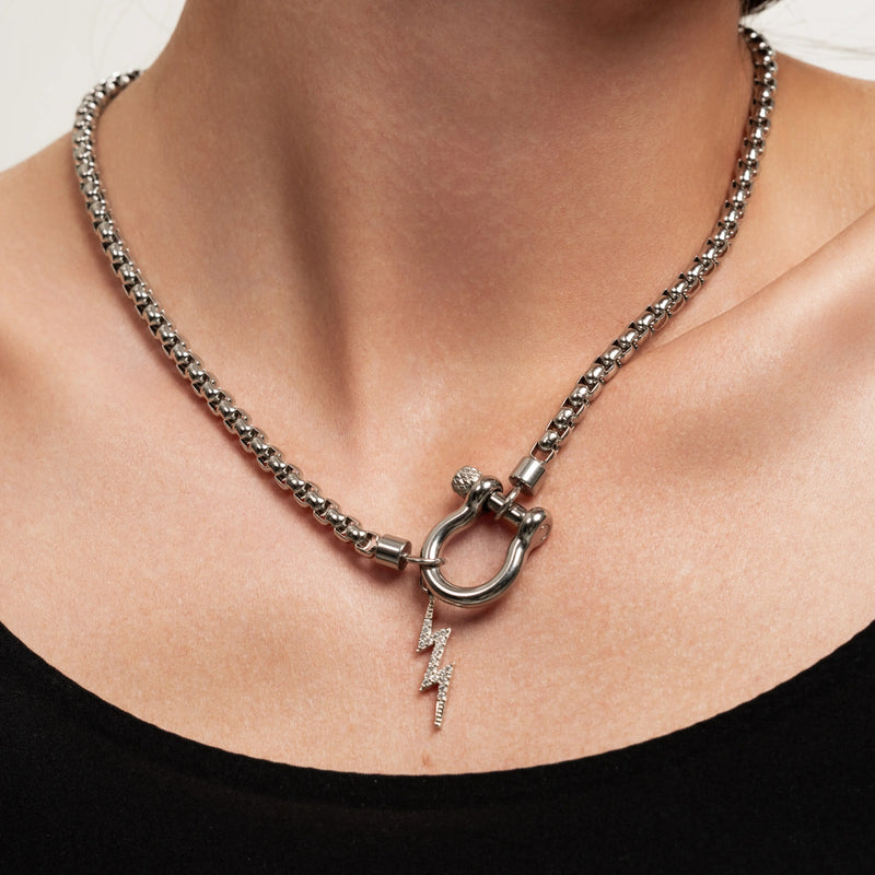 The Herradura Thunder Silver, which is a bold silver chain necklace featuring a toggle clasp with a lightning bolt pendant, worn by a woman in a black off-shoulder top.