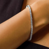 The Tennis Bracelet, which is a single elegant silver-tone bracelet featuring a continuous row of sparkling cubic zirconia stones, designed for timeless sophistication and versatility.