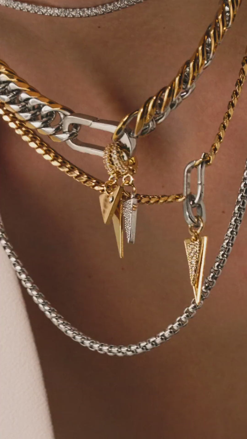Video of a model wearing The Triangle Necklace Set, a three-piece necklace set with gold and silver chains, including a cuban link, a box chain, and a tennis chain with triangle spike charms.