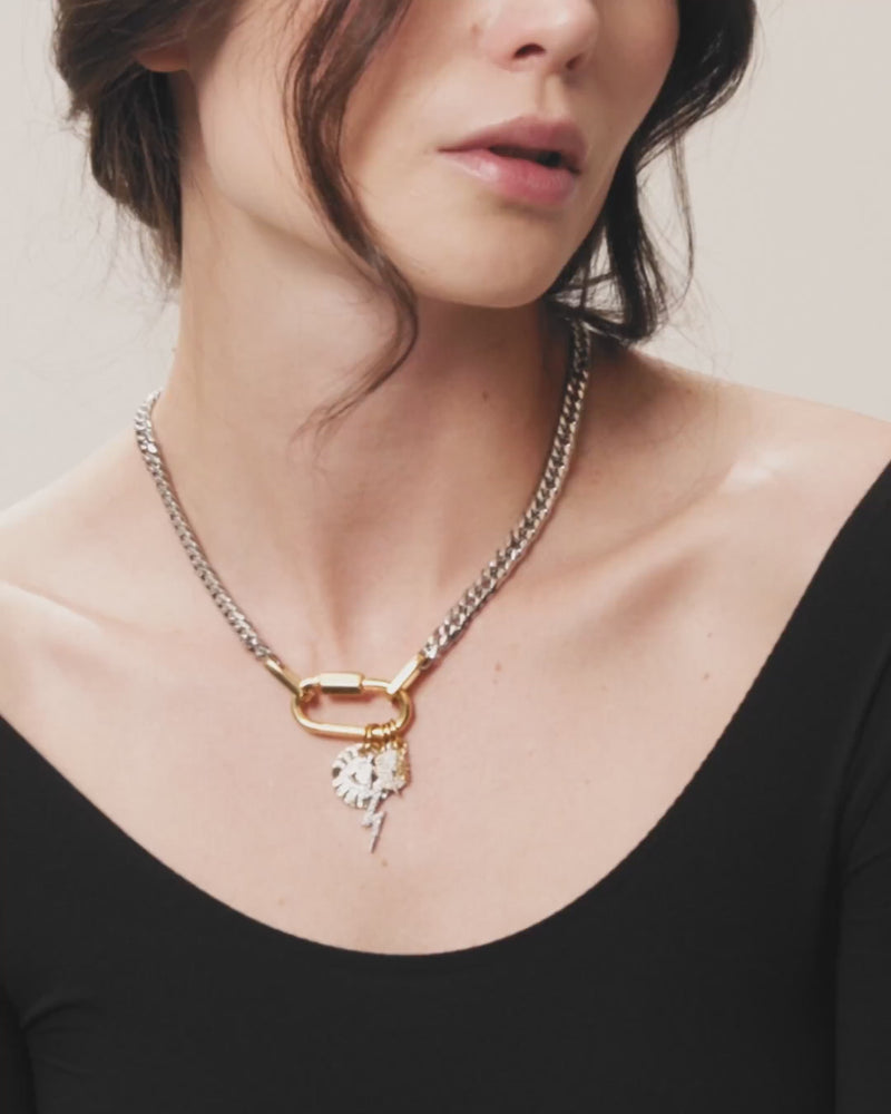 The Anne Charm Necklace, which is a delicate silver chain necklace featuring a multiple charm pendant, worn by a woman in a black top.