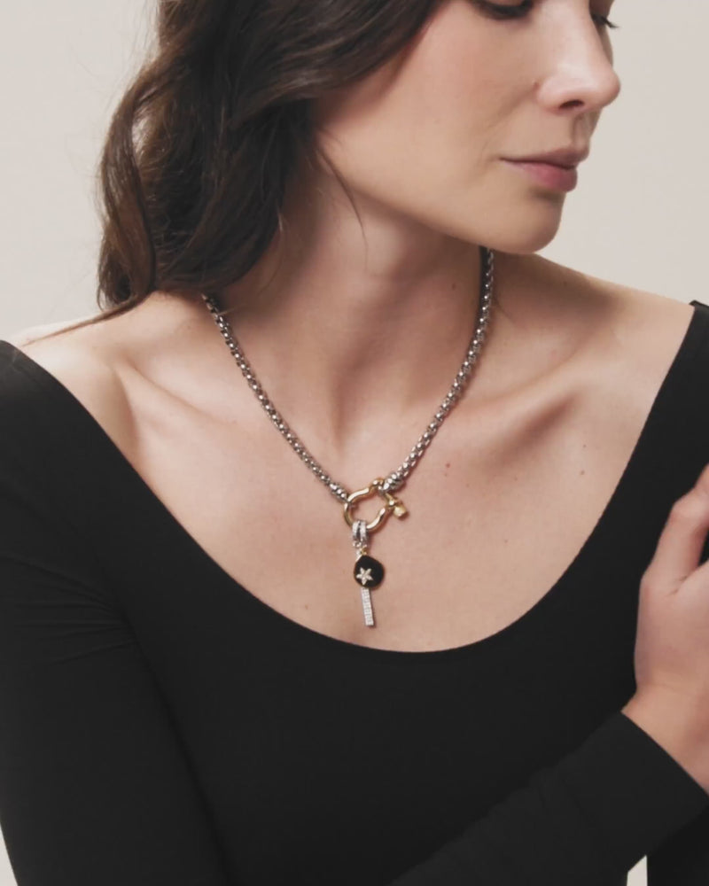 The Herradura Signature Double Take Necklace, which is a single-piece mixed metal necklace featuring a silver chain with a gold clasp and two detachable charms—a black round charm with a star detail and a pavé vertical bar. ||| GOLD