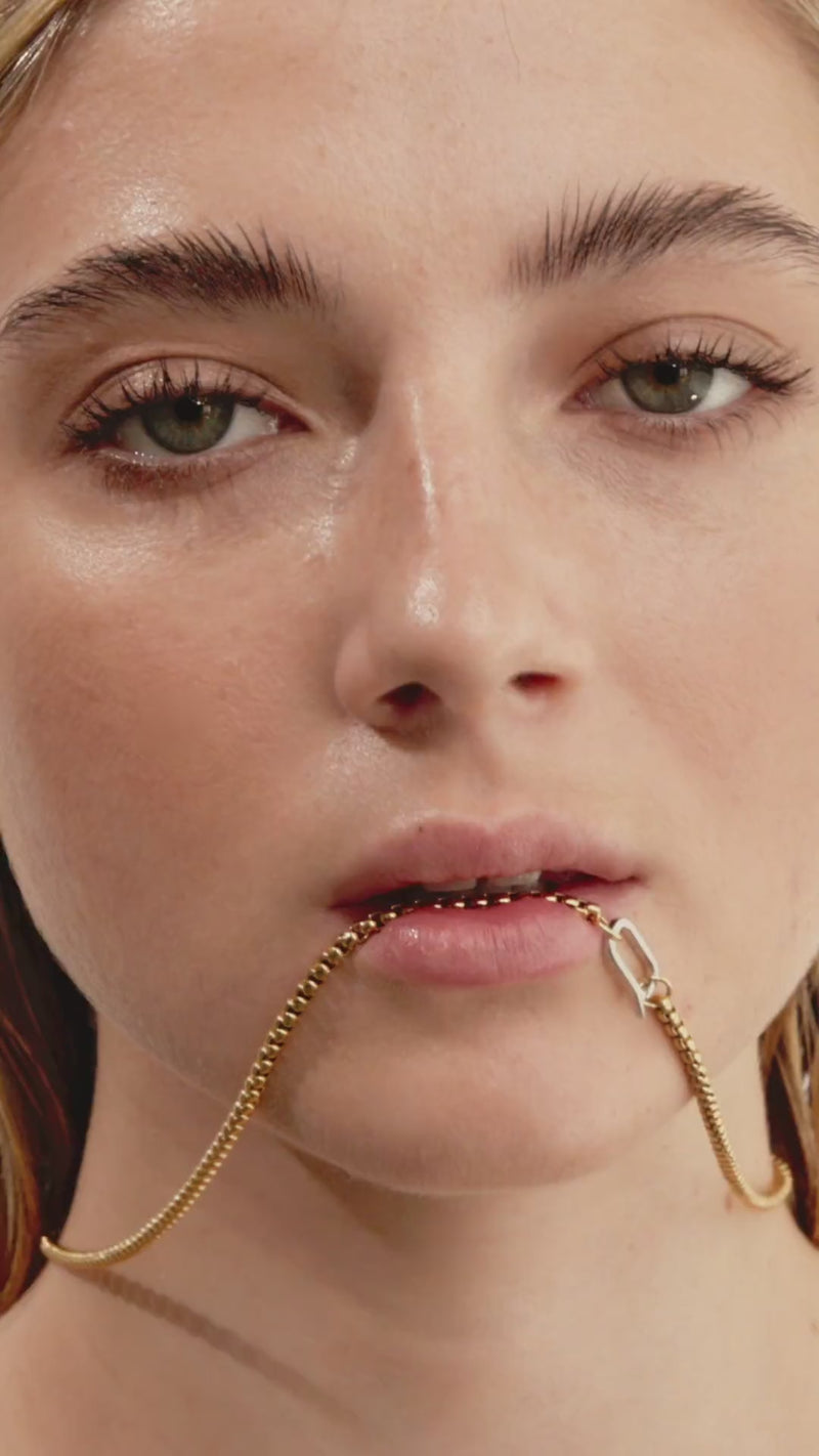 Video of a model wearing the Sleek Can Opener Snake Chain Necklace featuring a delicate, gold snake-like link chain design and a silver can opener secure clasp.