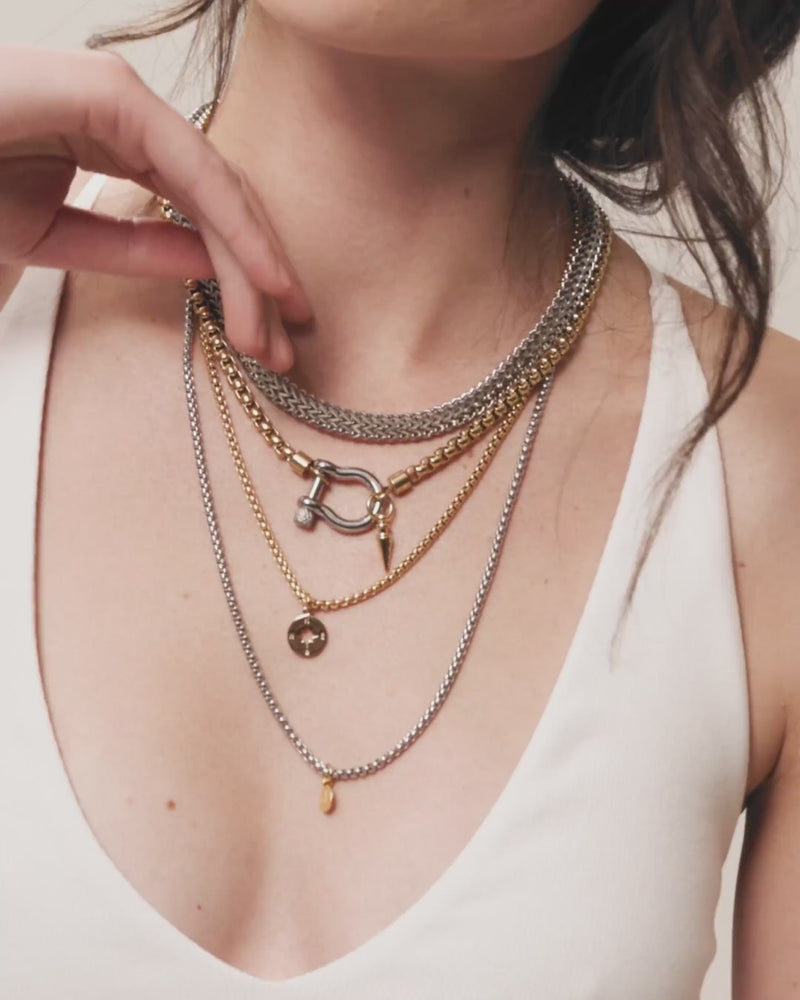 Model wearing the Herradura Layered Necklace Set featuring five mixed metal gold and silver chains with charms and a signature carabiner clasp. ||| SILVER