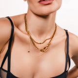 Model wearing the Sleek Carabiner Emerald Layered Necklace Set featuring four gold chains with emerald stone details and a bold carabiner clasp.
