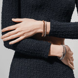 Model wearing a **four-piece bracelet stack** in mixed metals, featuring two gold and two silver bracelets with curb chain and pavé details. ||| SILVER