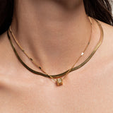 The You and the Snake Layered Necklace, which is a set of 2 layered gold necklaces featuring a sleek snake chain, a delicate chain with geometric accents, and a fine chain with a small engraved pendant.
