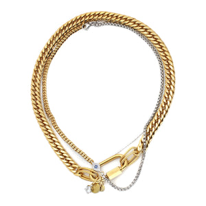 The Maya Layered Necklace Set, a three-piece gold and silver necklace set featuring a Cuban link chain, a box chain, and a rope chain with a lobster clasp closure, a diamond-like accented evil eye charm, and a disc charm.