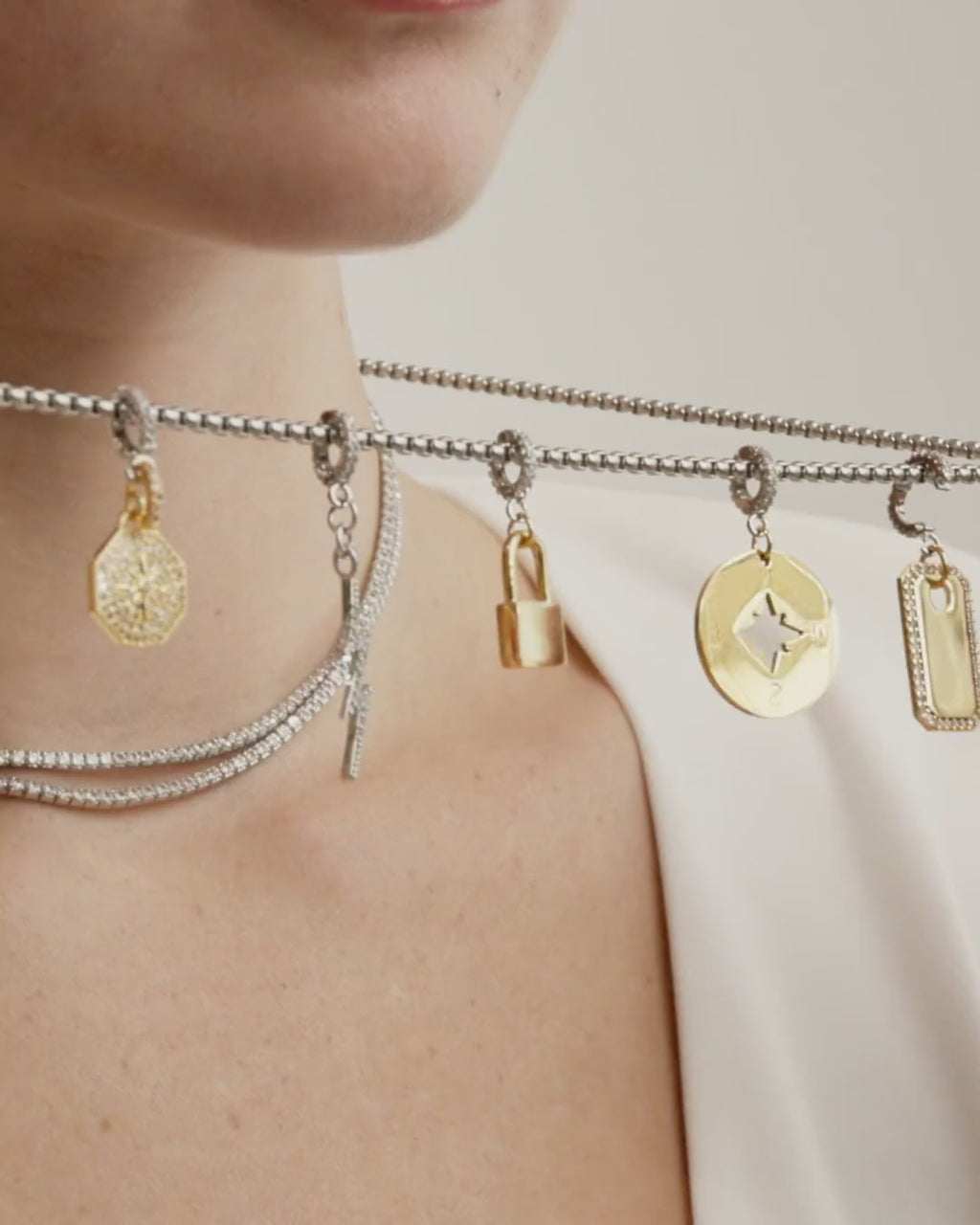 Video of a model wearing tennis necklace set with long silver chain with charms. It comes with the north, lock, compass, plaque clip on and the LIGHTNING BOLT CLIP ON CHARM which is made of Pave Clip on Stainless steel 18k gold plated lighting bolt charm.