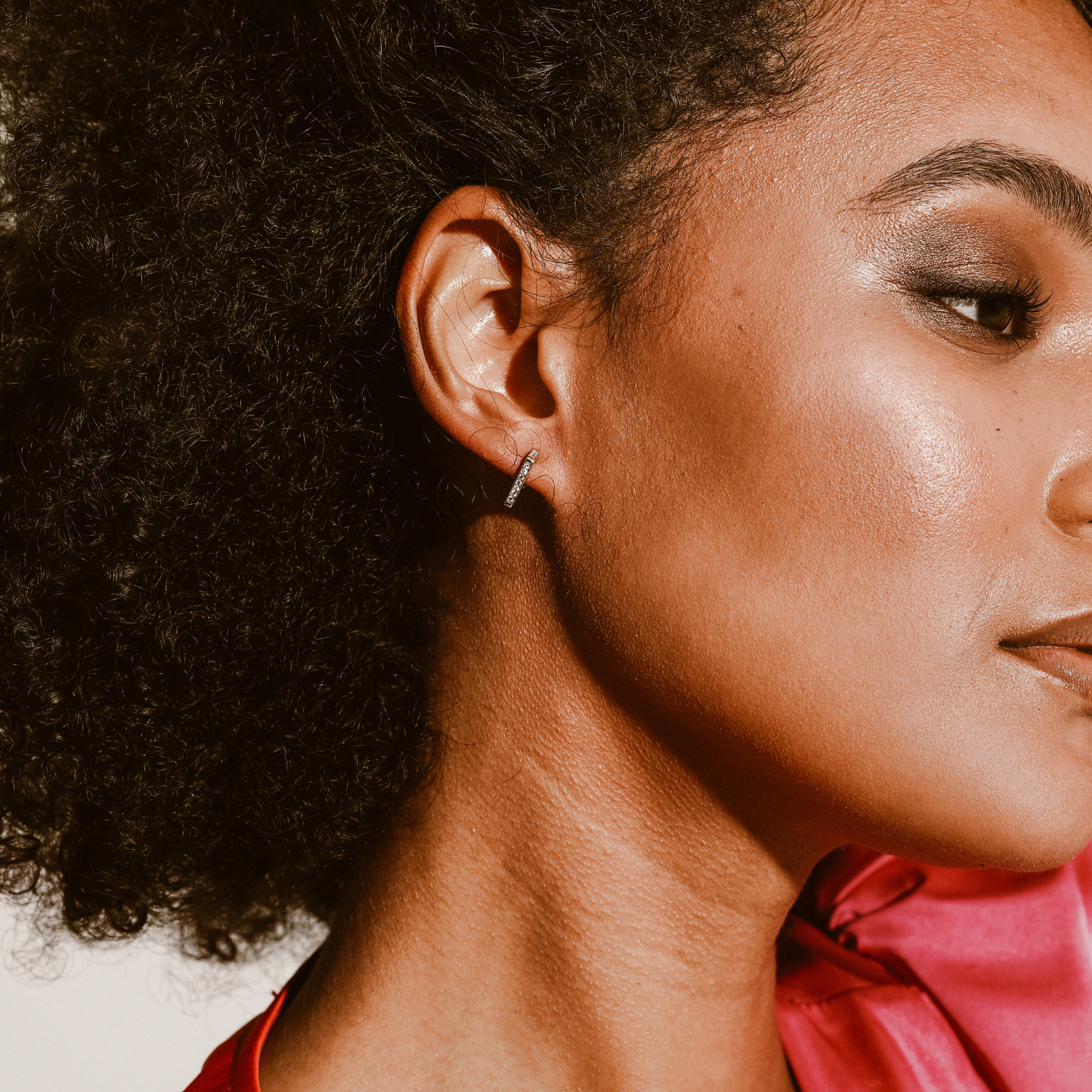 Model wearing the The TRIANGULO HUGGIES which is made of 925 sterling silver triangular shaped earrings covered with cubic zirconia. The width is 13.mm / 0.5in and has a drop of 11mm / 0.4in.