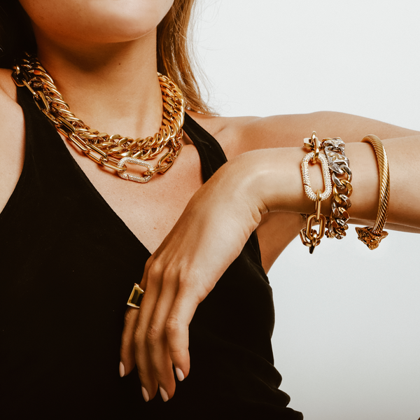 Model wearing a black halter top accessorized with the Puerto Fino Necklace in gold plated stainless steel with a Micro Pave Zirconia lock and the Palma necklace. She is also wearing the Palma bracelet, Puerto Fino Bracelet and the Lion bracelet.