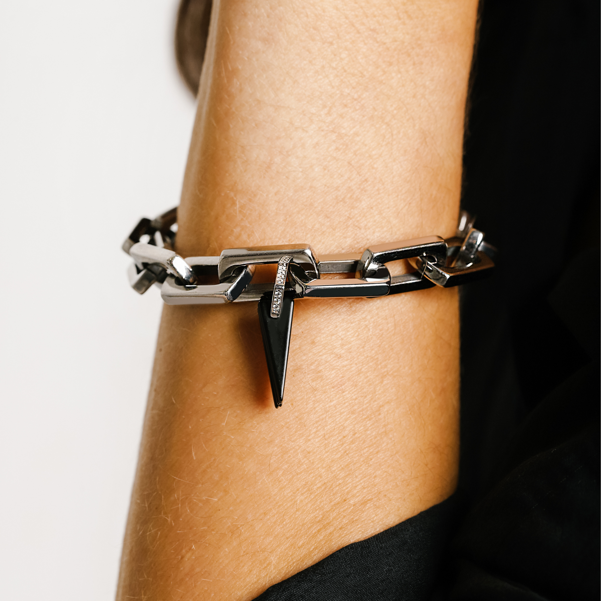 Model wearing the Light Bracelet Silver which is 8 inches in length, Stainless steel link chain with Black Triangle charms & Zirconia.