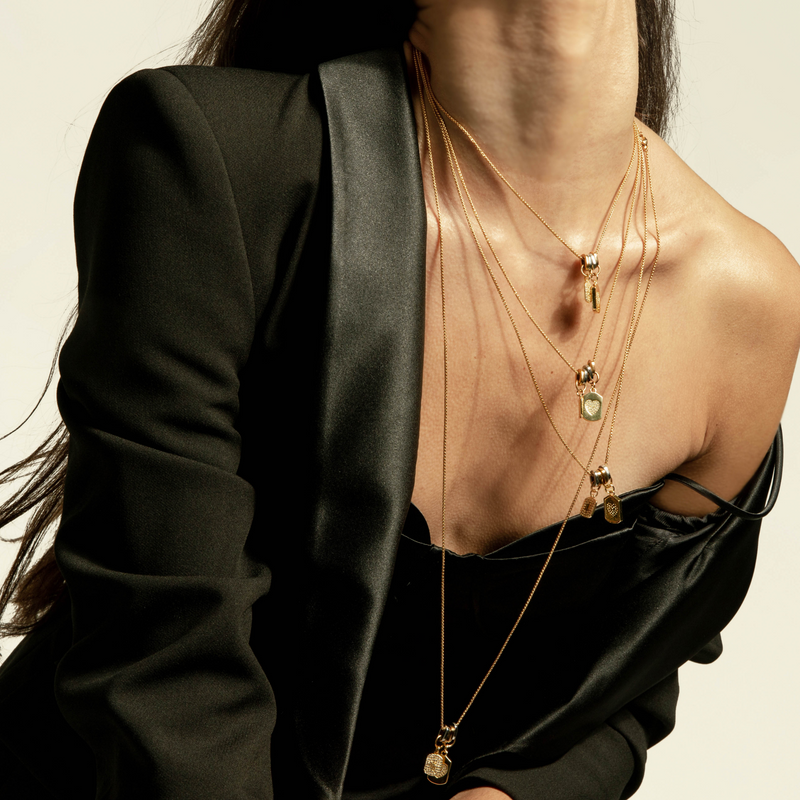 Model wearing four single charm necklaces in different sizes. They are 1mm wide each, made of Stainless steel 18K gold plated chains with two dainty gold filled charms.