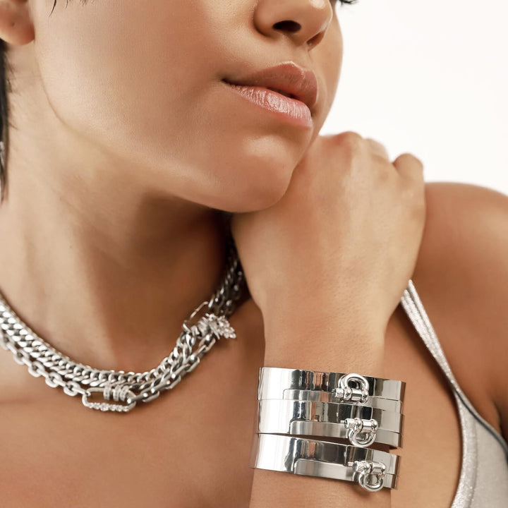 Model wearing 3 Herradura Bangles, a silver bangle bracelet with a prominent, horseshoe-shaped clasp and the Just Click  Necklace and Puerto Shine in Silver. ||| SILVER