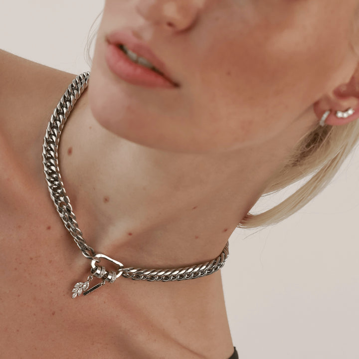 The JUST CLICK SPIGA CHAIN, a single chunky silver chain necklace featuring a pave-accented clasp adorned with two sparkling charms, offering a bold and stylish statement piece.