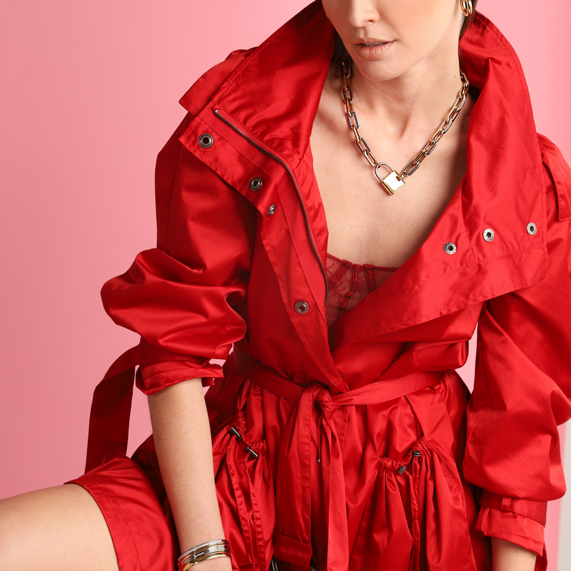 Model in red jacket wearing the PUERTO LOCK NECKLACE which has a chain made of mix silver and gold links and Stainless steel 18k gold plated lock pendant.