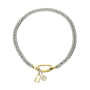 ANNE CLIP ON LOCK NECKLACE: A statement necklace featuring a thick, mixed-metal chain in silver and gold tones. The centerpiece is a gold carabiner clasp adorned with a diamond-encrusted padlock charm and a circular pendant also embellished with diamonds.