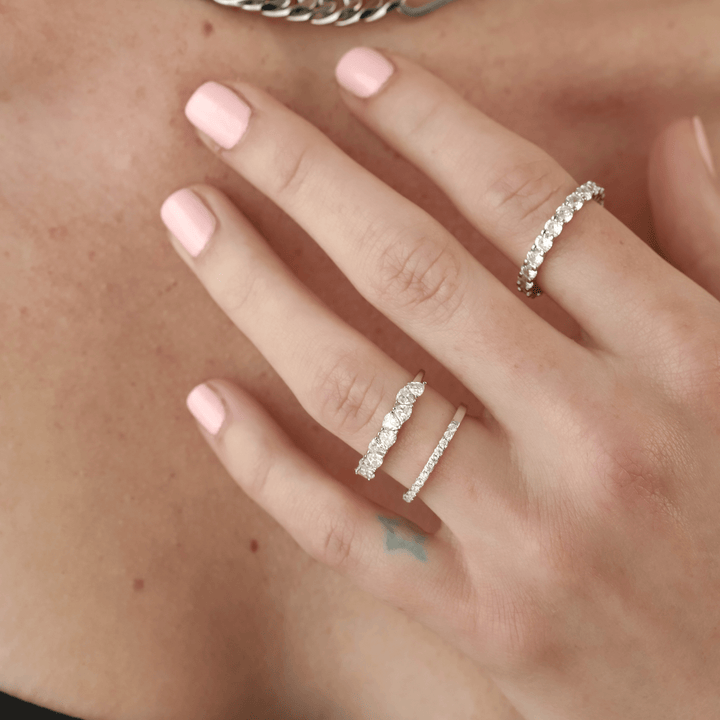 Model wearing 3 eternity bands. One thin band, a full eternity band and the Half Eternity Band Ring, a silver ring featuring a half-circle of sparkling diamond-like stones.