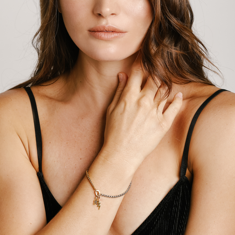 Model is wearing the SHAKERATO BLENDED BRACELET which is a 7" half stainless steel chain and half stainless steel 18k gold plated chain with an 18k gold plated zirconia star pendant, and gold plated lightning pendant.