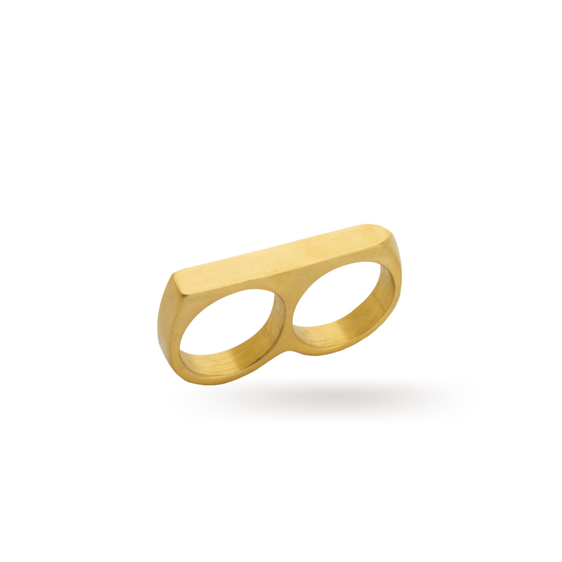 The FERVENT RING which is a double ring made of 18k gold plated stainless steel. It has a flat surface covering two fingers when worn.