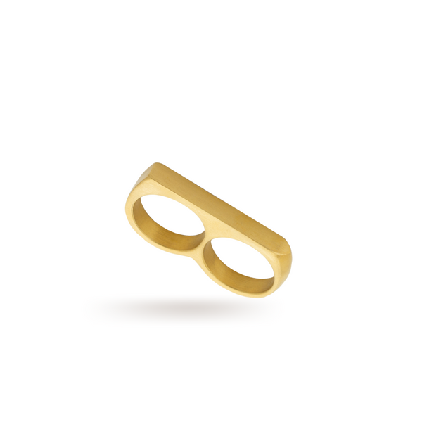 The FERVENT RING which is a double ring made of 18k gold plated stainless steel. It has a flat surface covering two fingers when worn.
