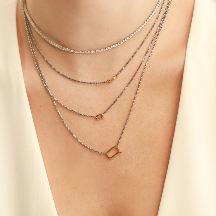 Model wearing three Can Opener Necklaces in different lengths and sizes featuring a refined thin silver link chain design and a secure gold can opener clasp. She is also wearing a thin tennis necklace. ||| GOLD
