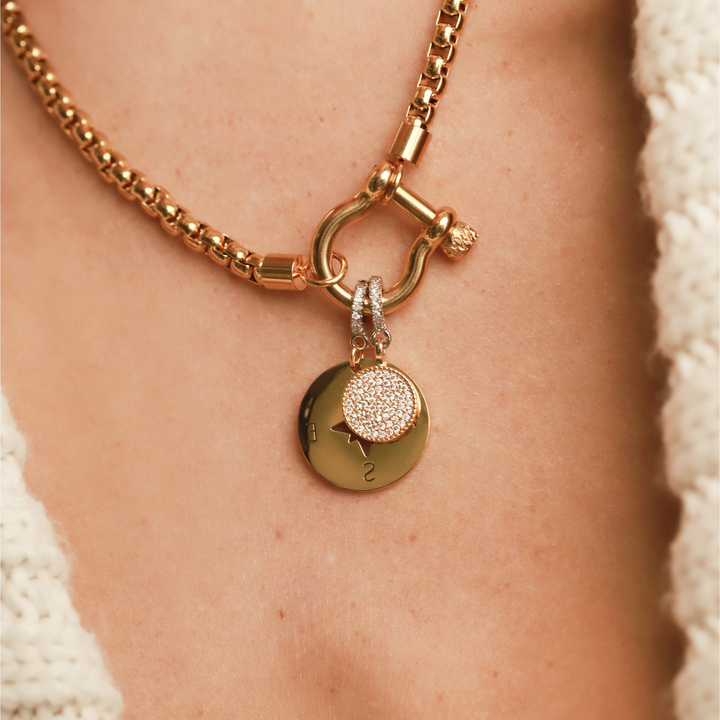 Model wearing the Herradura Necklace with the Compass charm and The Circle Clip-On Charm, which is a two-toned charm featuring a circular gold pendant paved with sparkling diamonds and a silver clip embellished with a row of smaller diamonds.