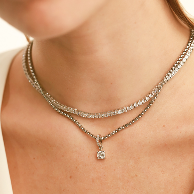 Model wearing layered necklace set which includes the Tennis Necklace and stainless steel silver chain with The SOLITAIRE CLIP ON CHARM which is made of Pave clip on Stainless steel solitaire charm that is 20mm in length. 