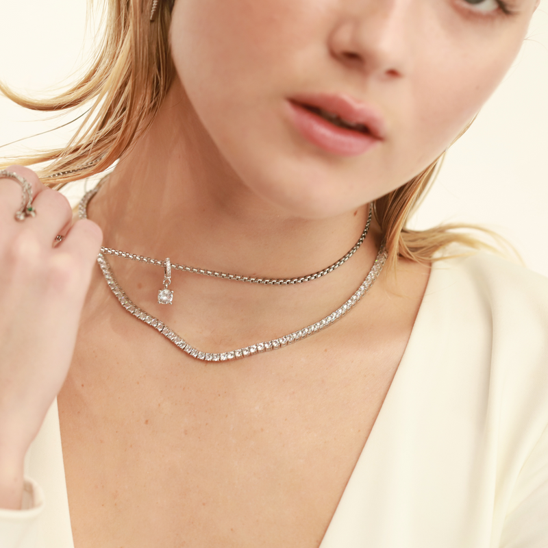 Model wearing layered necklace set which includes the Tennis Necklace and stainless steel silver chain with The SOLITAIRE CLIP ON CHARM which is made of Pave clip on Stainless steel solitaire charm that is 20mm in length.