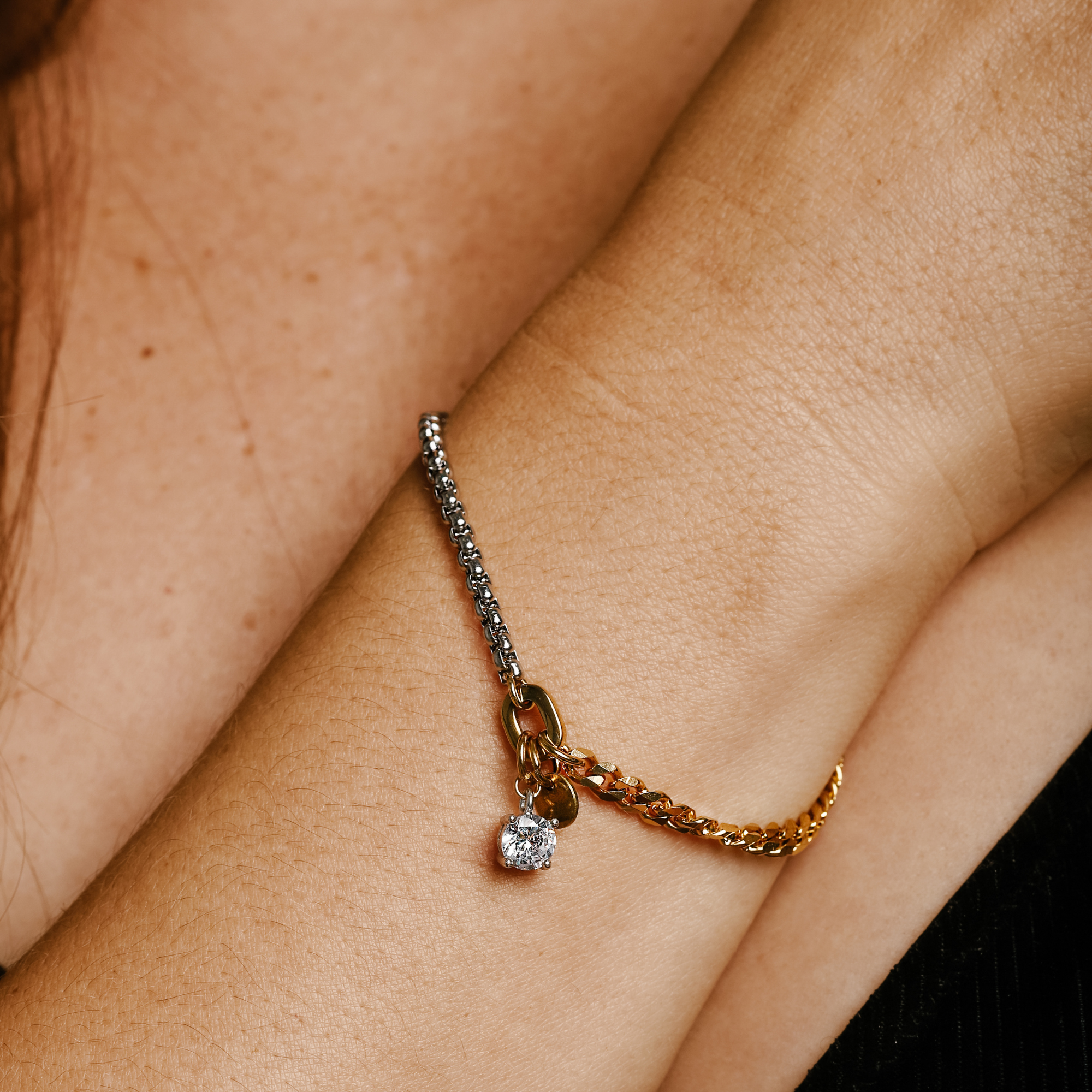 Model wearing the LUNGO BLENDED BRACELET which is a 7" bracelet made of half stainless steel and half 18k gold plated chain with Zirconia pendant solitaire and brass raw coin.
