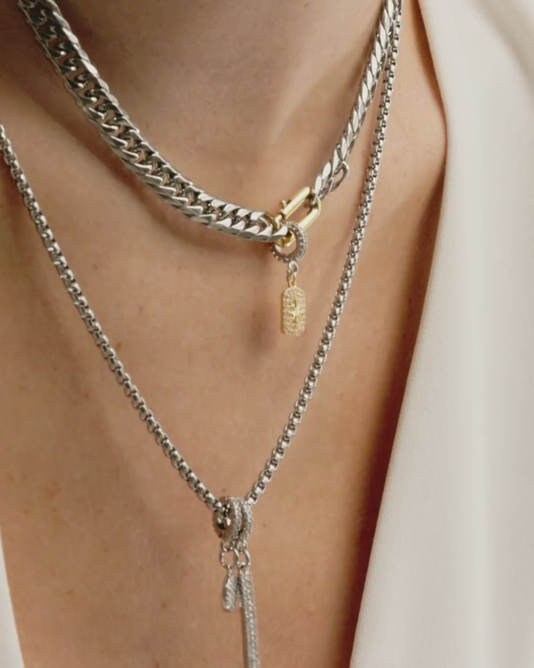 Video of a model wearing two silver necklaces with different charms including the Celestial Star Clip On Charm, a gold charm with a  star design accented with pave diamonds and a silver clip-on bale.