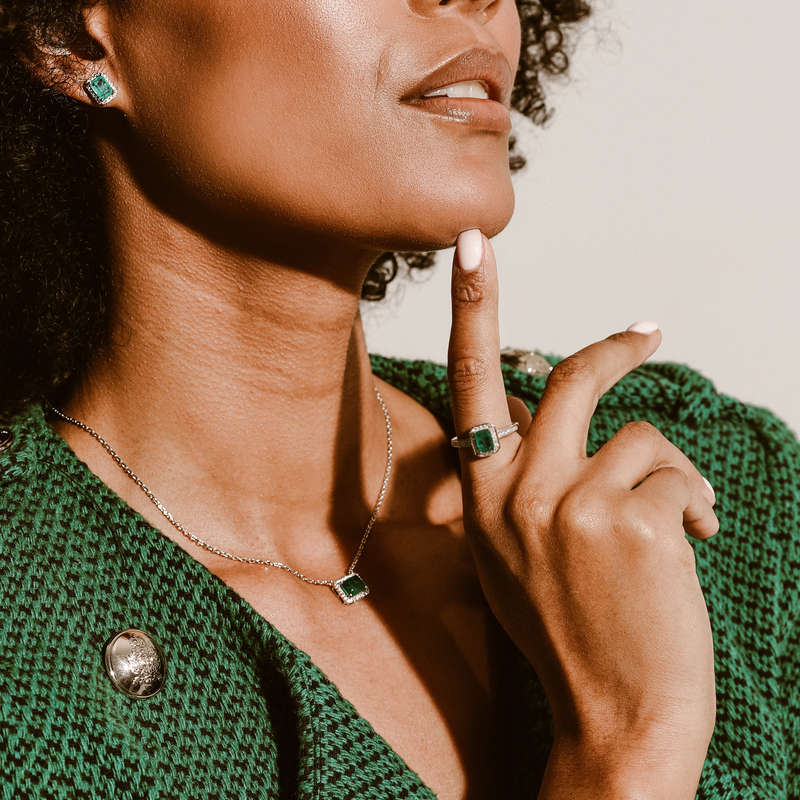Model wearing an EM STUD EARRINGS which is made of 925 sterling silver, cubic zirconia and square man made emerald stone. She is also wearing the Em cut ring and the EM Necklace.