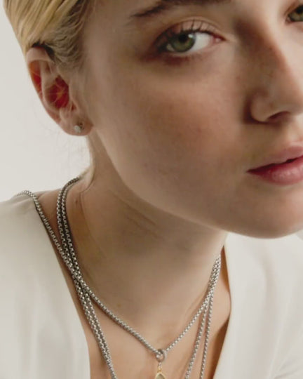 Video of a model wearing layered necklaces with the Drop Star Clip On Charm, a gold charm with a teardrop shape, a diamond-encrusted star, and a silver clip-on bale.