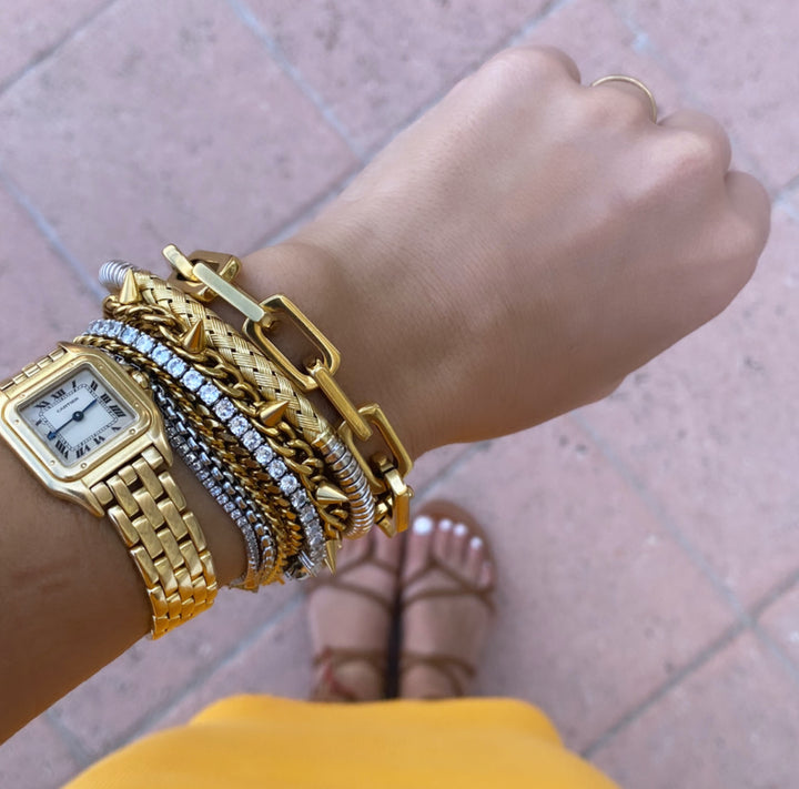 Model wearing a watch and the BLENDED LUX SET which comes with 4 bracelets. The Crema blended which is half silver and gold with gold plated zirconia evil eye pendant, Marocchino blended which is an 18k gold plated chain with Zirconia solitaire,star and spike charms, tennis bracelet which is made of Rhodium-plated brass/cubic zirconia and Lungo blended bracelet which is Half stainless steel and half 18k gold plated chain with cubic zirconia and coin charms.