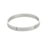 The Lane Bangle, which is a sleek silver bangle, features a minimalist design with a row of five sparkling stones set into its surface. The silver tone adds elegance and versatility, making it perfect for any occasion.