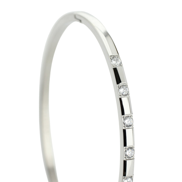 The SEQUENCE BANGLE which is made of rhodium plated Stainless steel with seven Cubic zirconia and dimensions of 2.8" x 1.77". ||| SILVER