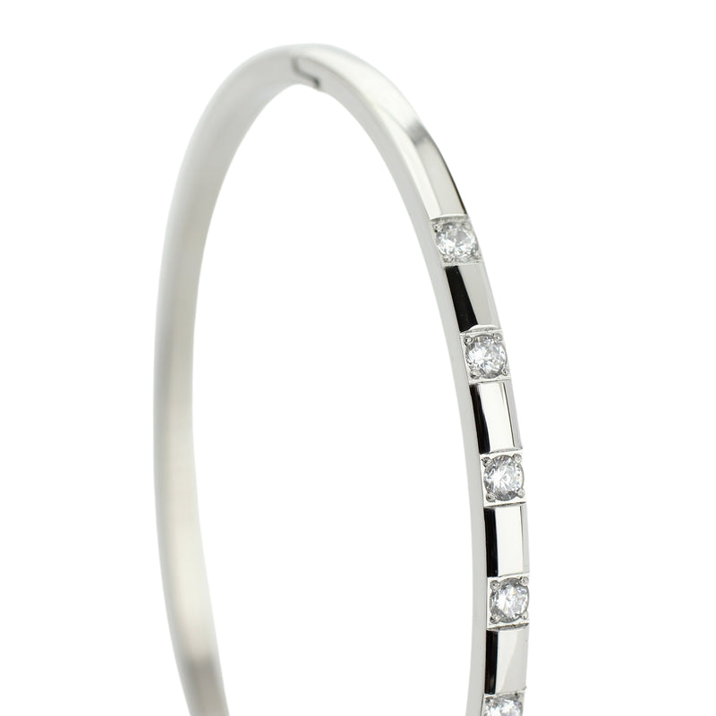 The SEQUENCE BANGLE which is made of rhodium plated Stainless steel with seven Cubic zirconia and dimensions of 2.8" x 1.77".